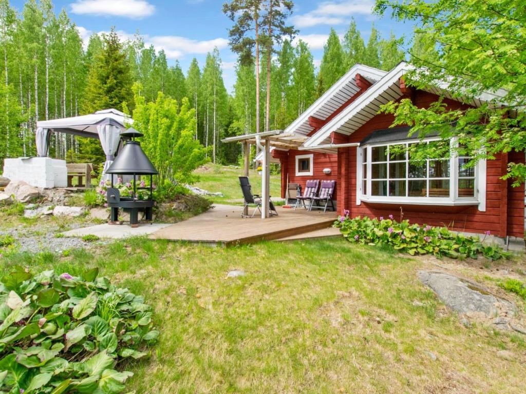uma pequena casa vermelha com um deque e um grelhador em Holiday Home Cjoe239 by Interhome em Pölläkkä