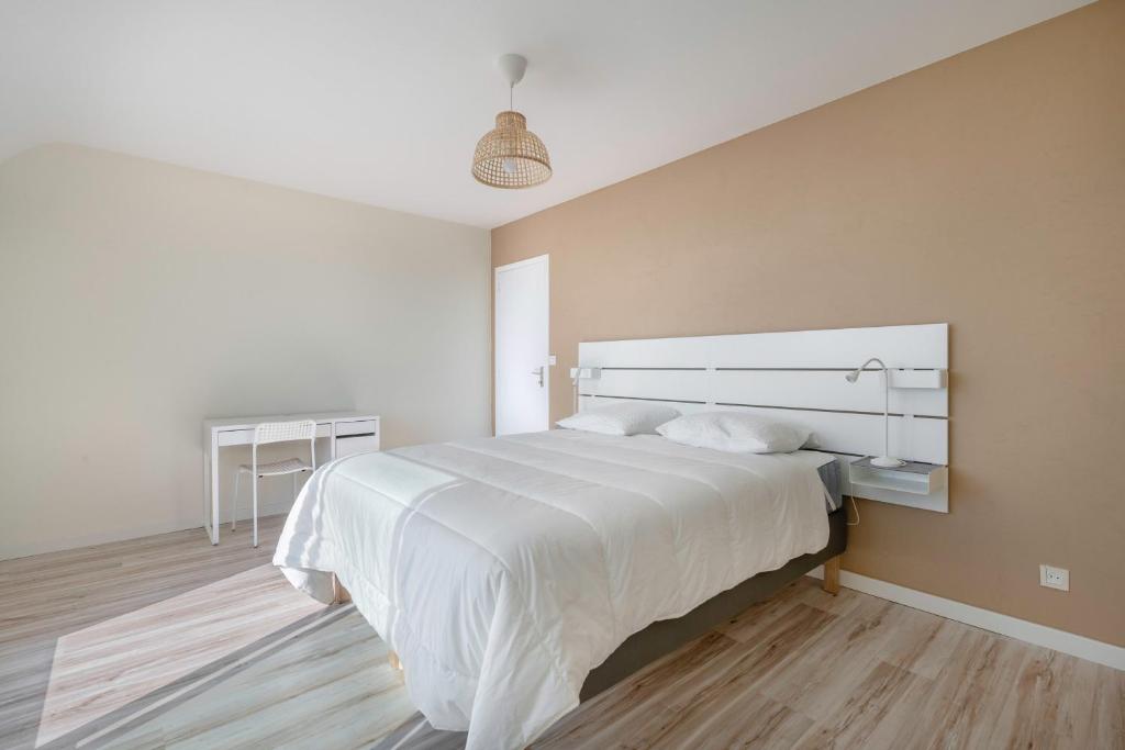 a bedroom with a large white bed and a desk at Parenthese relaxante les pieds dans l eau in Le Tour-du-Parc