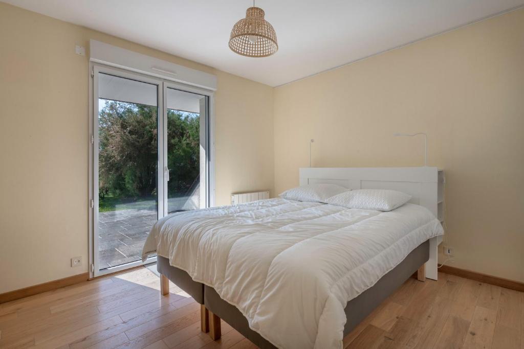 a bedroom with a large bed and a large window at Parenthese relaxante les pieds dans l eau in Le Tour-du-Parc