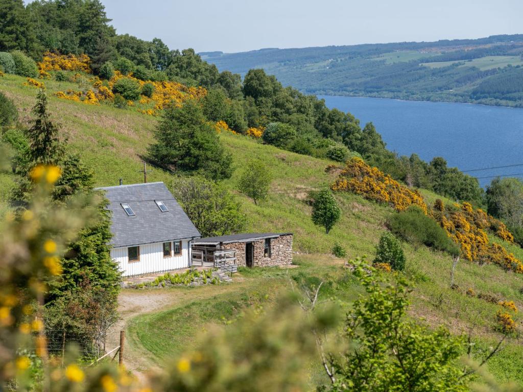 a house on the side of a hill with a lake at Holiday Home Peter's Shed by Interhome in Drumnadrochit