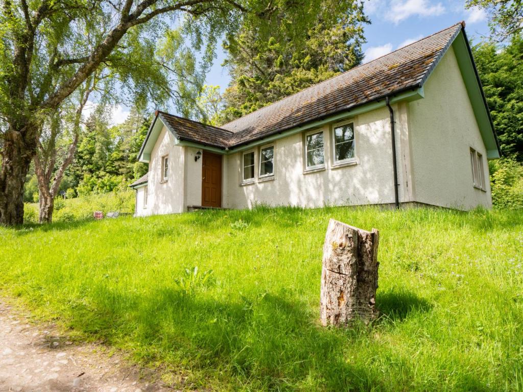 a small house in a field with a tree stump at Holiday Home The Firs by Interhome in Drumnadrochit