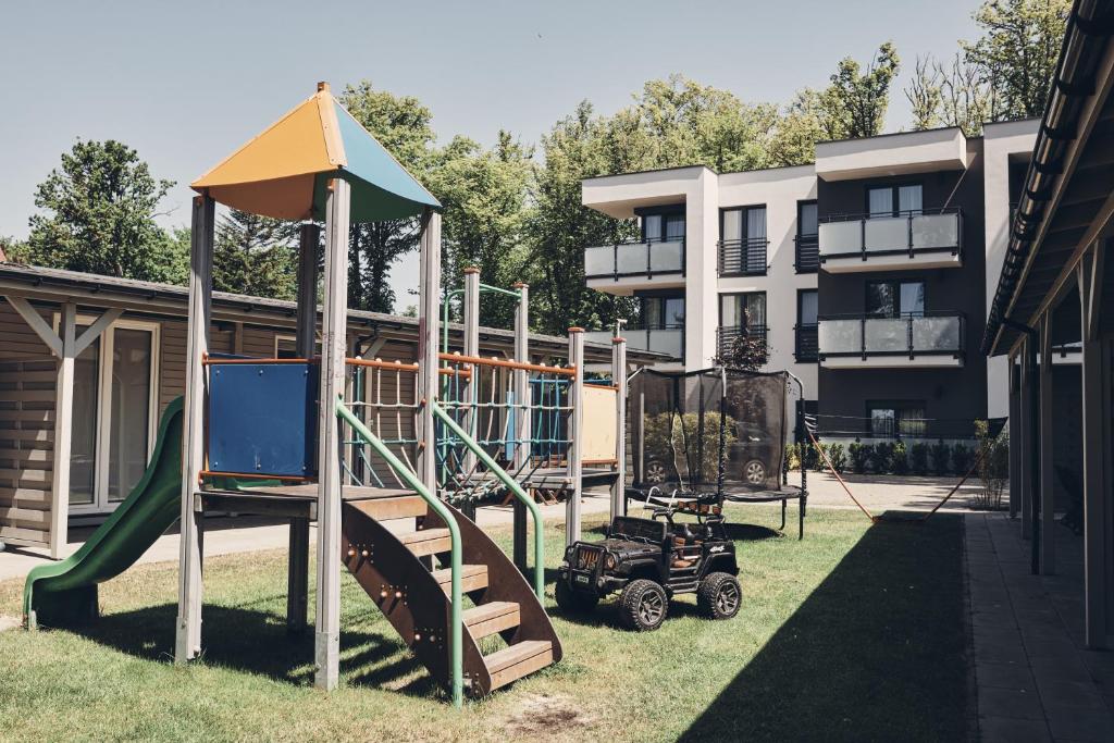 un parque infantil frente a un edificio con tobogán en Holiday Siesta Pensjonat, Domki en Rewal