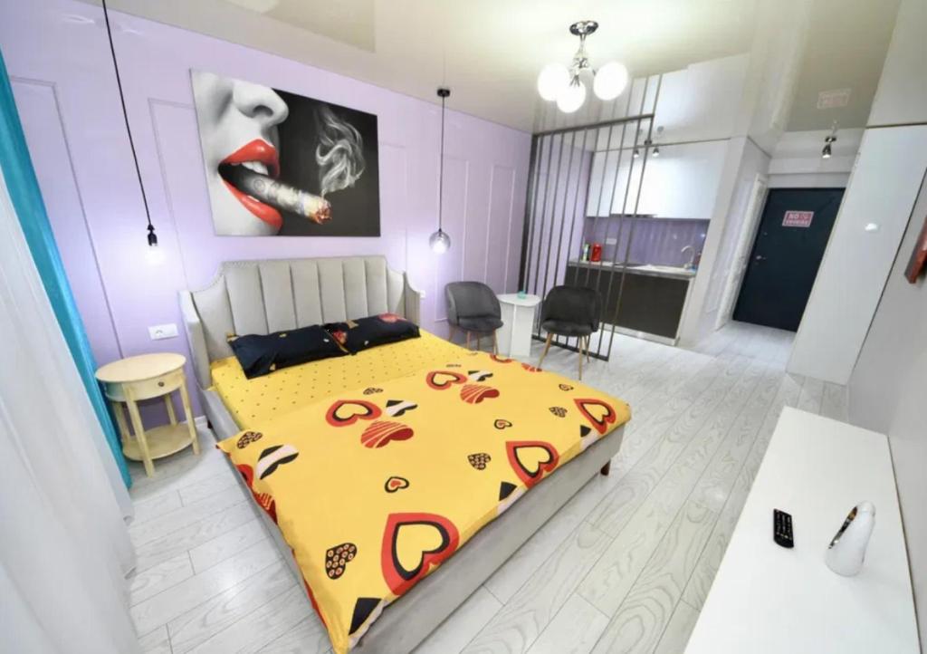 a bedroom with a bed with a yellow comforter and a kitchen at Glamour in Năvodari