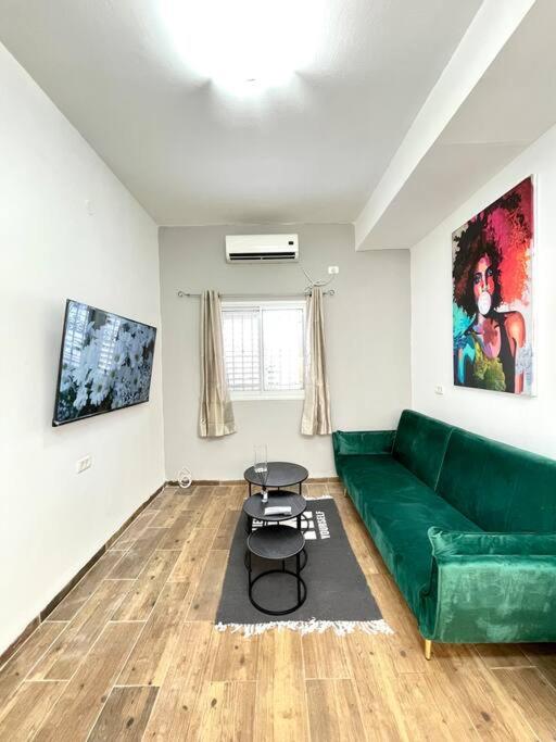 een woonkamer met een groene bank en een tafel bij Bat Galim BEACH apartment in Haifa