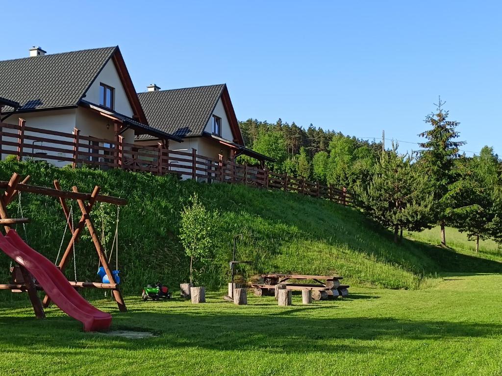 uma casa numa colina com um parque infantil em Bieszczadzki Bohater Domki 533-502-137 em Polańczyk