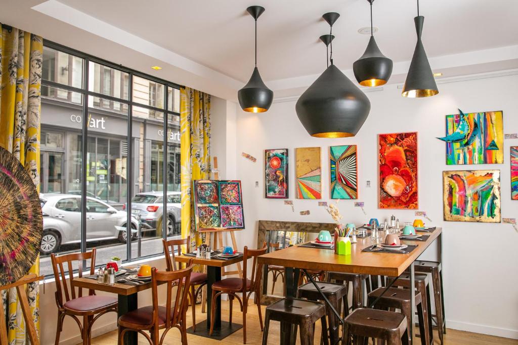 a restaurant with tables and chairs and a window at Hôtel Crayon in Paris