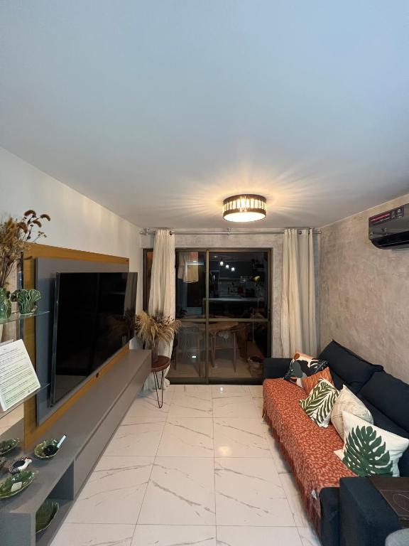 a living room with a couch and a tv at Nannai Residence - Apartamento Duplex in Porto De Galinhas
