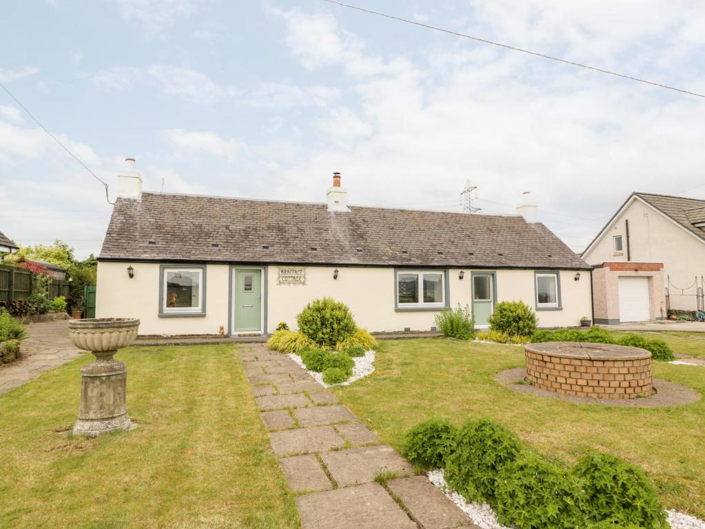 a white house with a garden in front of it at Braeface Cottage in Bonnybridge