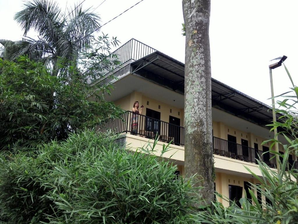 a woman standing on a balcony of a building at Hotel Cemerlang in Baturaden