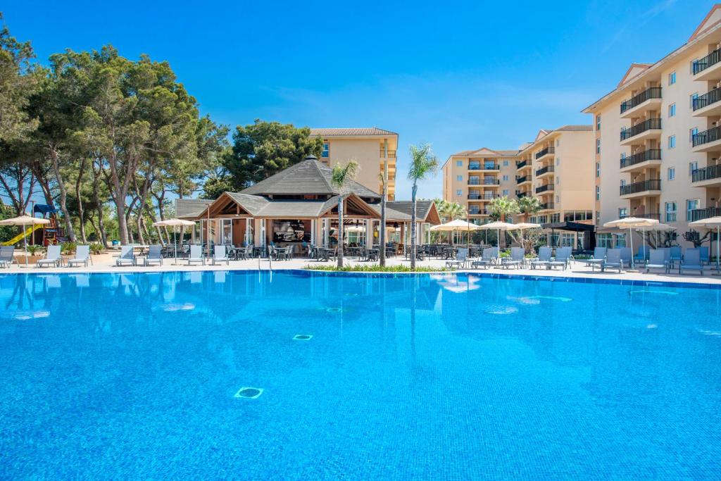 a large blue swimming pool with chairs and umbrellas at Can Picafort Palace in Can Picafort