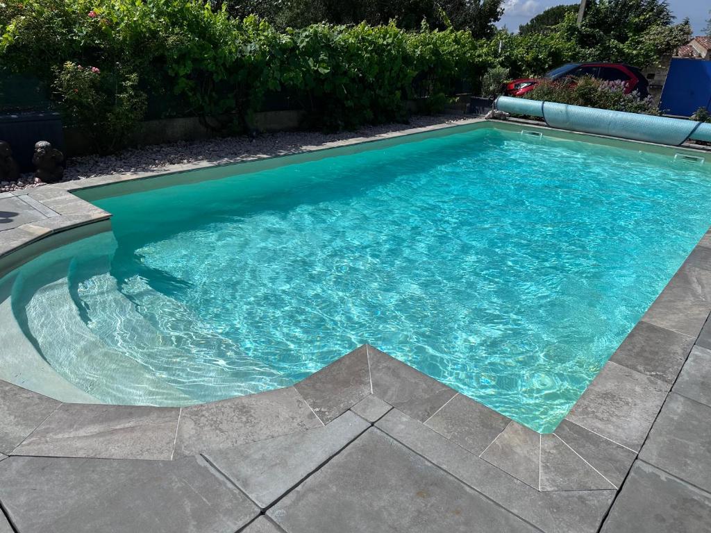 a swimming pool with blue water in a yard at Studio les Iris climatisé, entre mer et collines, classé meublé de tourisme 2 étoiles in Allauch