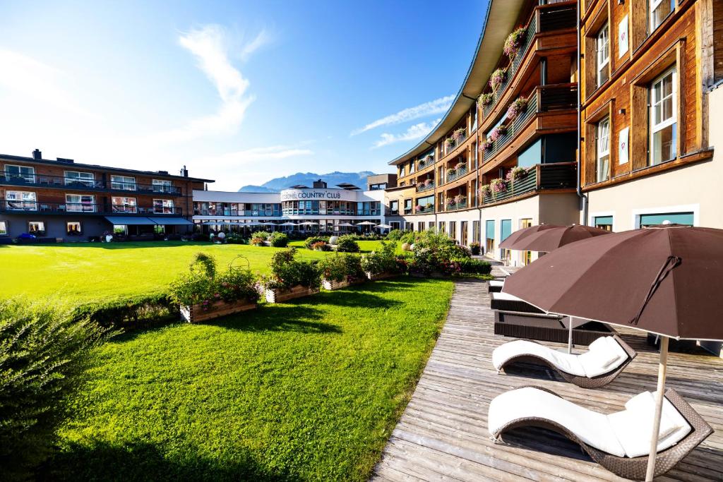 un patio con sillas, sombrilla y césped en Kitzbühel Residences, en Kitzbühel