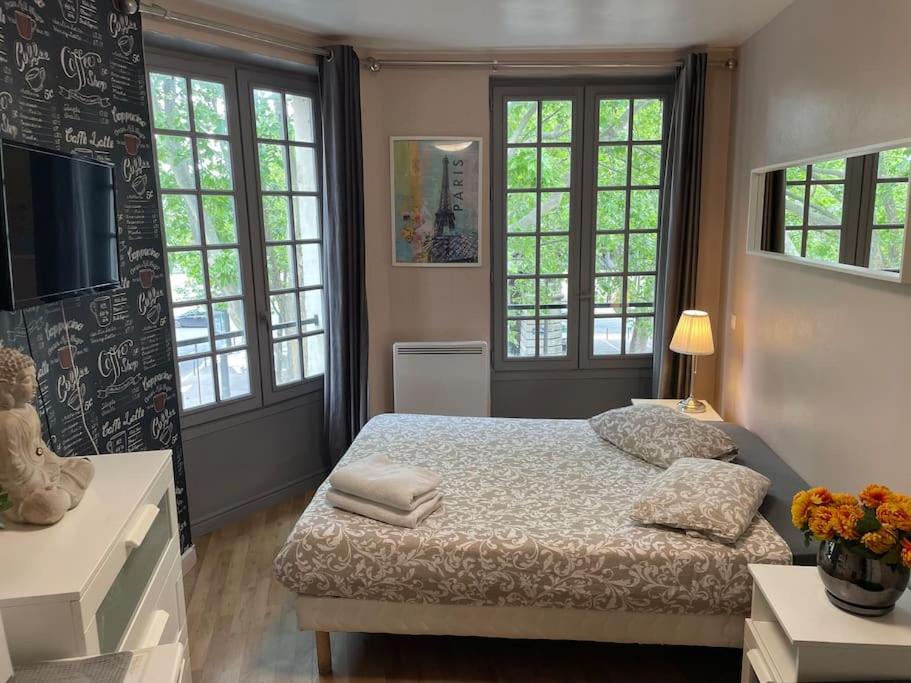 a bedroom with a bed and two windows at Studio Montsouris in Paris