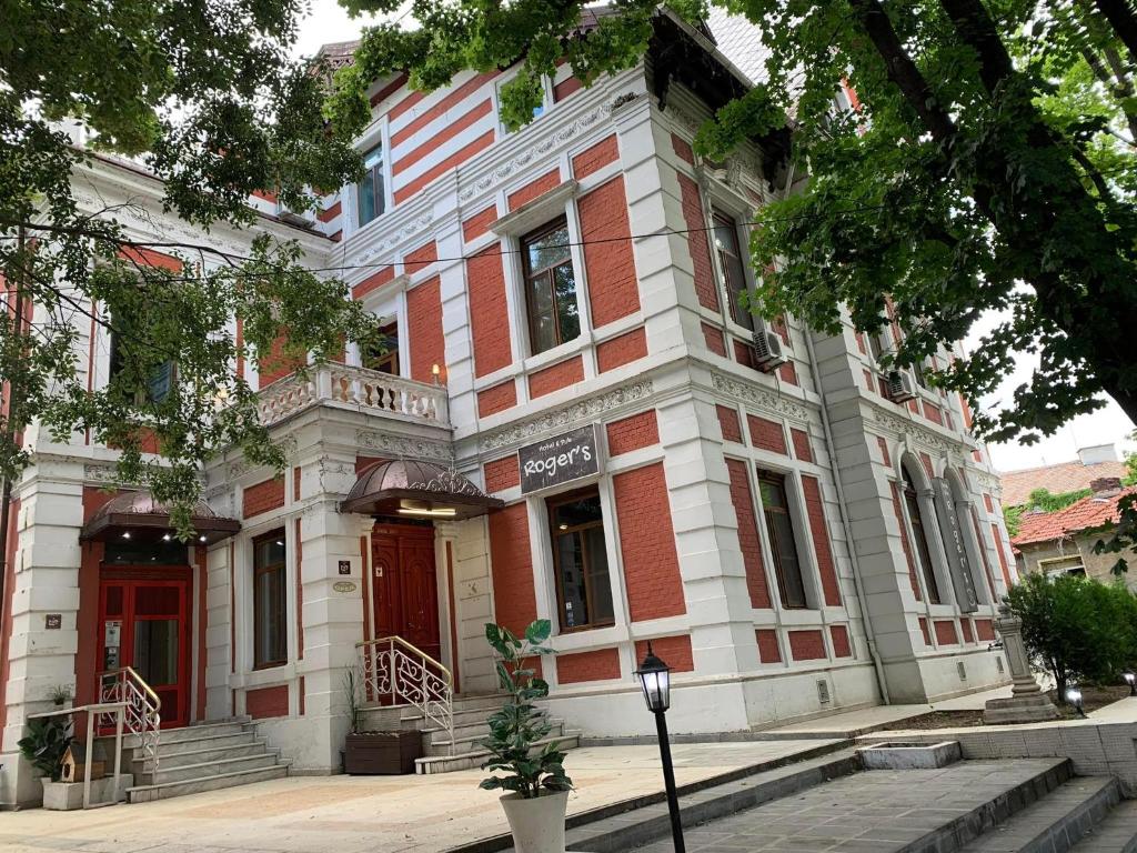 un grand bâtiment rouge et blanc dans une rue dans l'établissement Roger's Hotel, à Ruse