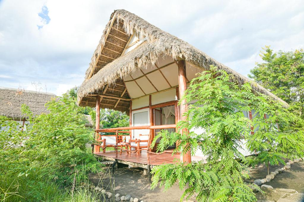 a house with a thatched roof with a deck at Kazinga Wilderness Safari Camp in Kasese
