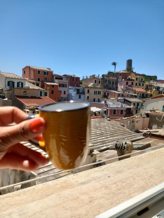 een hand met een kopje koffie en uitzicht op de stad bij Da Isabella in Vernazza