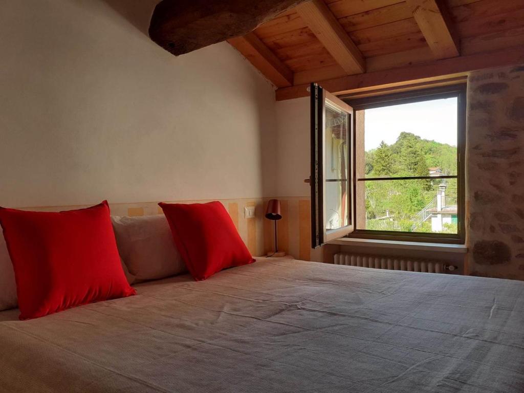 um quarto com uma cama grande com almofadas vermelhas e uma janela em La Casa Torre em Pignone