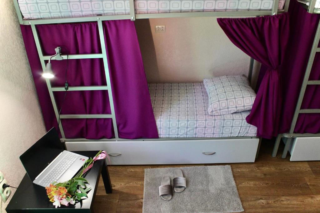 a bedroom with a bunk bed with purple curtains and a desk at Kust Hostel in Kyiv