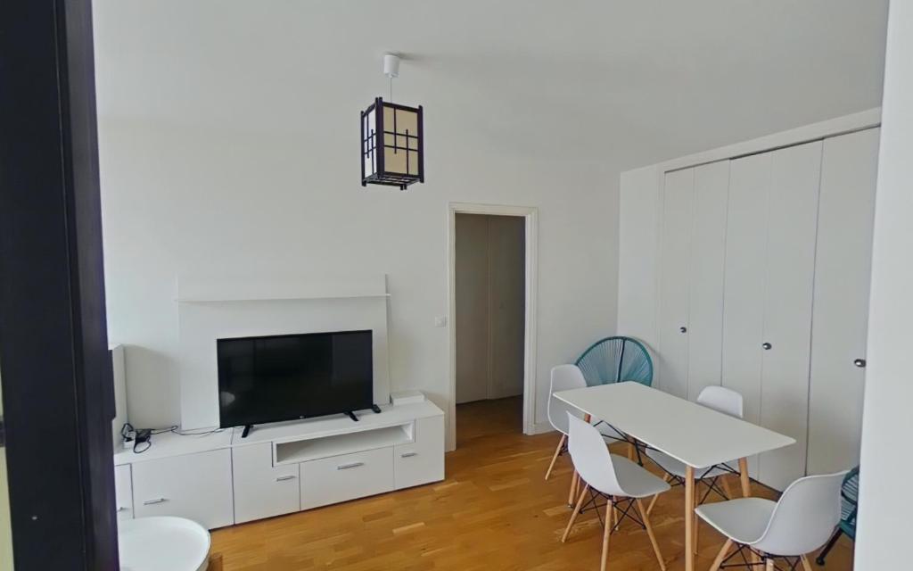 a living room with a tv and a table and chairs at Bright, contemporary apt in the Bel Air district in Paris