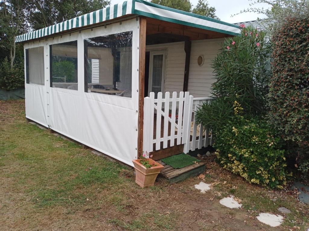 a white shed with a porch and a fence at MOBIL HOME dans Parc résidentiel Loisirs in Talmont