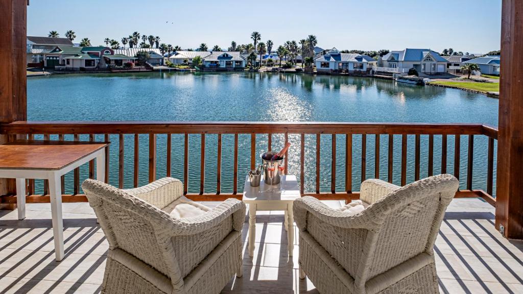 a balcony with chairs and a table and a view of a river at The Ark Guesthouse at Marina Martinique in Jeffreys Bay