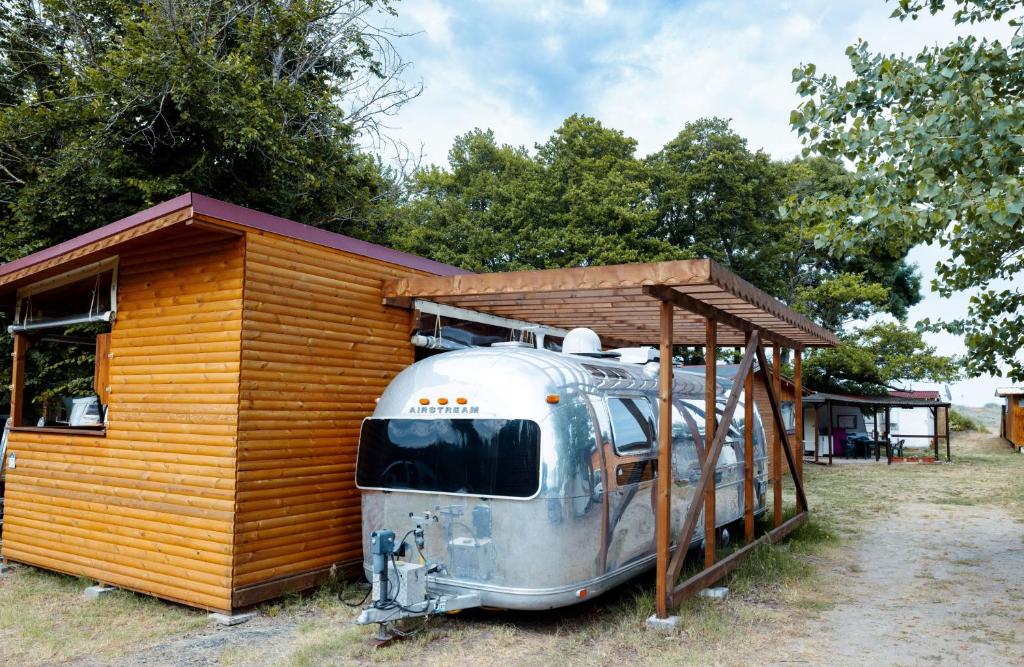 Una vieja cabaña con un cobertizo encima. en Luxury Vintage Airstream RV/Caravan Retro Charm Meets Comfort en Kiten