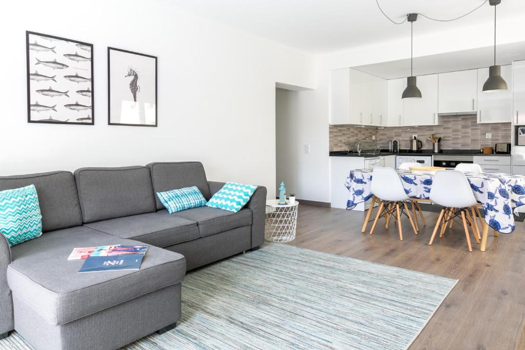 uma sala de estar com um sofá e uma cozinha em 1 Bedroom Beach Apartment with Balcony 2 min walk to the beach! em Costa da Caparica