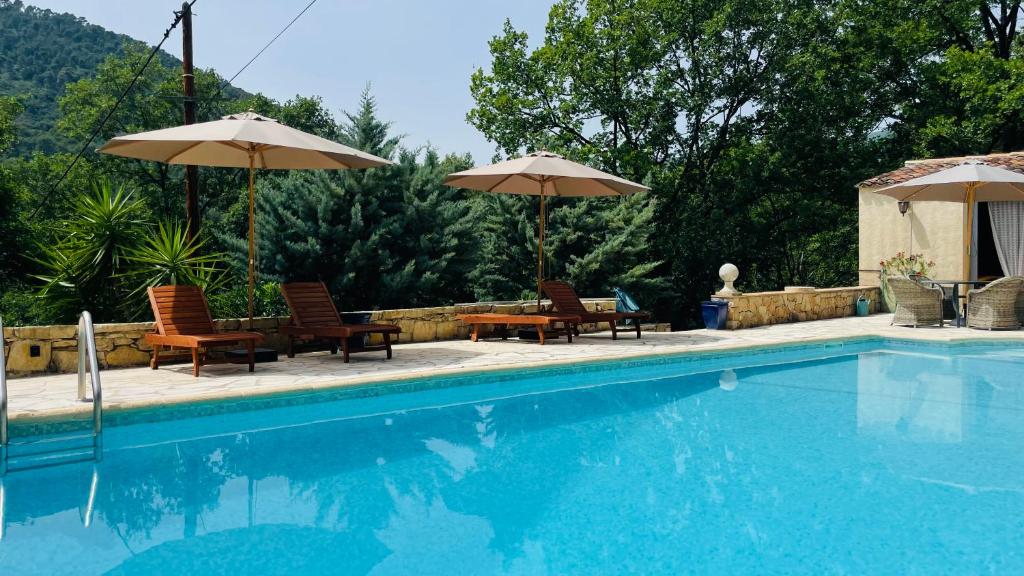 a swimming pool with chairs and umbrellas at VILLA CAU B&B - Les Anglores in Claviers