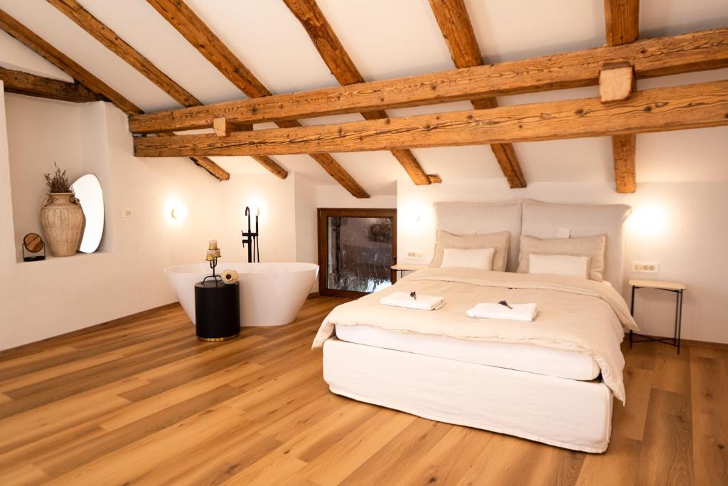 a bedroom with a large bed and a bathtub at Škerlj Wine Estate in Tomaj