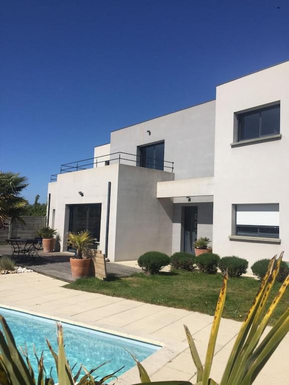 une maison blanche avec une piscine devant dans l'établissement Maison Moderne Avec Piscine Chauffée Dans la Baie du Mont st Michel 200m2, à Yquelon