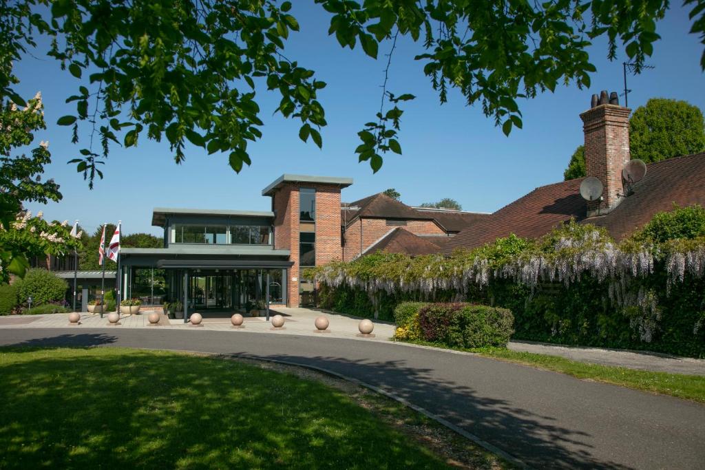 a house with a driveway in front of a building at Norton Park Hotel, Spa & Manor House - Winchester in Sutton Scotney