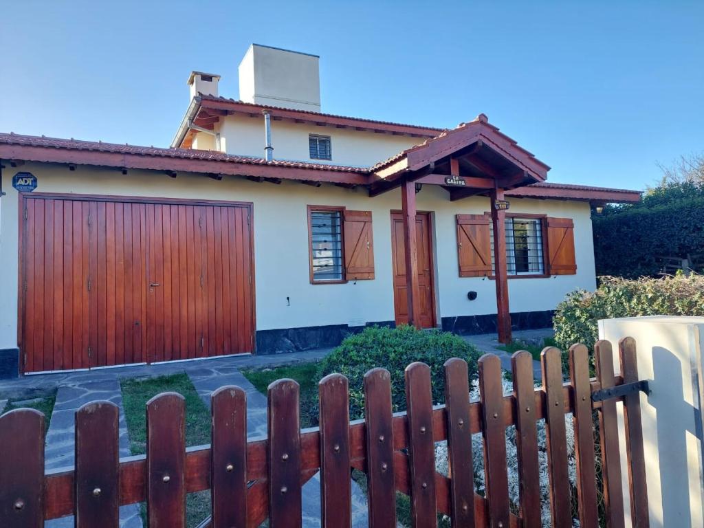 una casa con una valla de madera delante de ella en La Casita - Chalet de Montaña en Villa General Belgrano