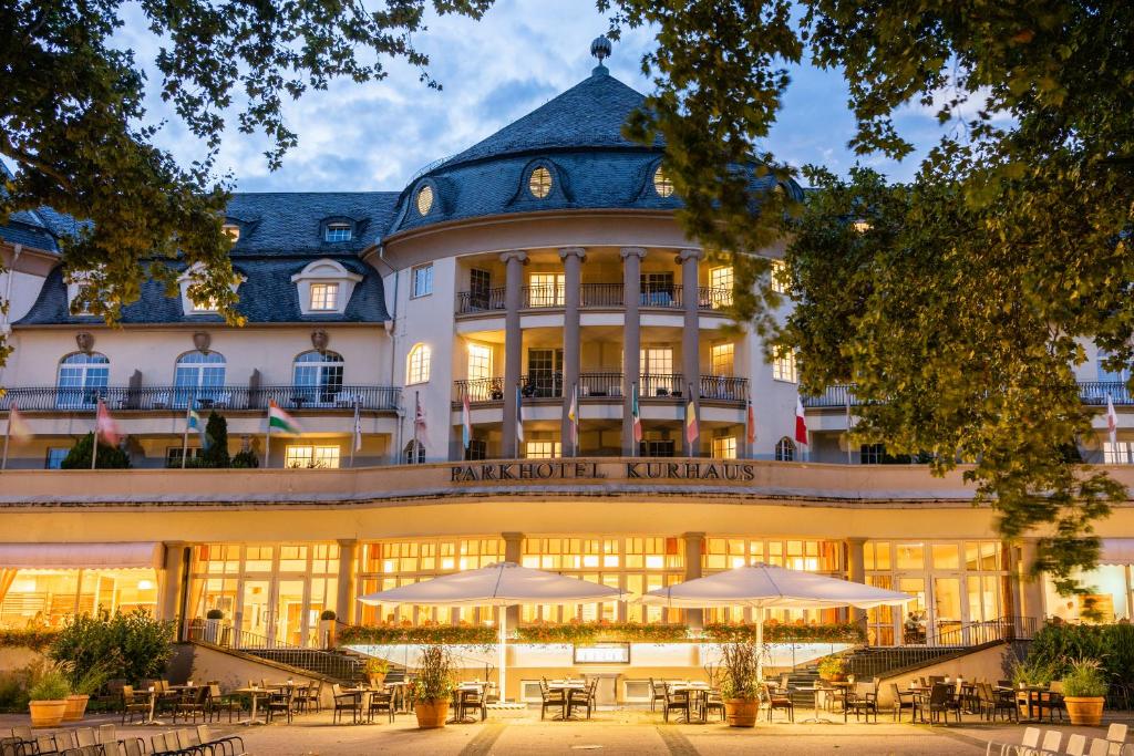 un bâtiment avec des tables et des parasols devant lui dans l'établissement Parkhotel Kurhaus, à Bad Kreuznach