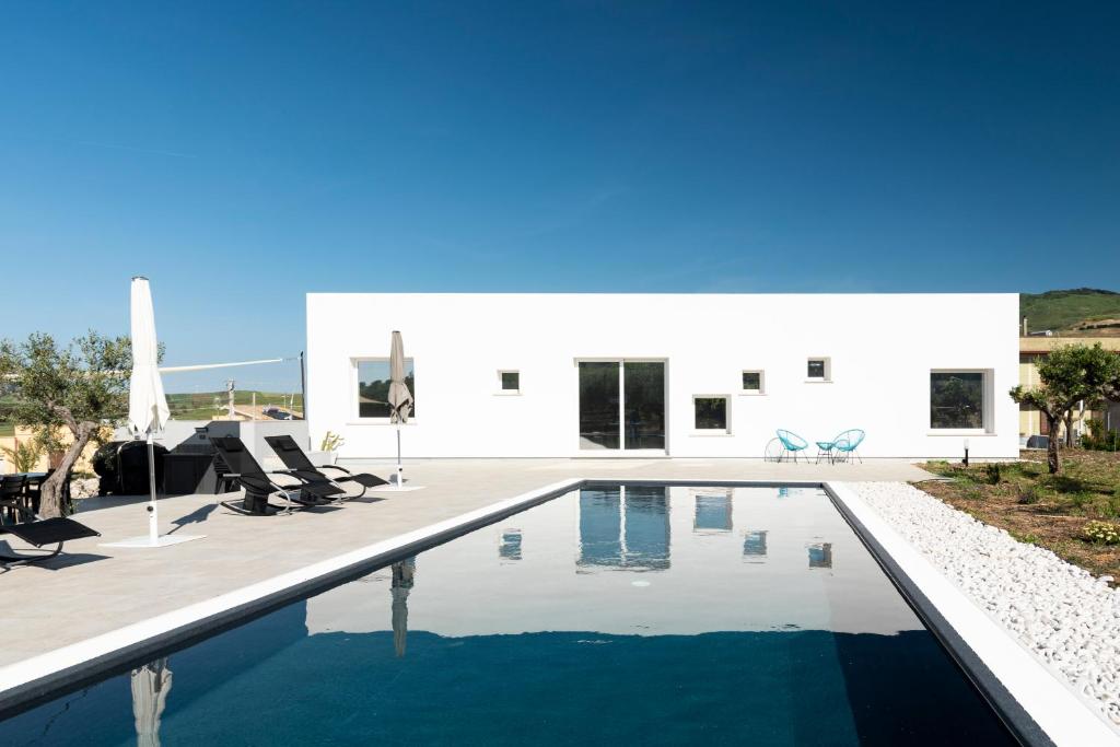 une piscine devant une maison blanche dans l'établissement Relais Donna Tana, à Buseto Palizzolo