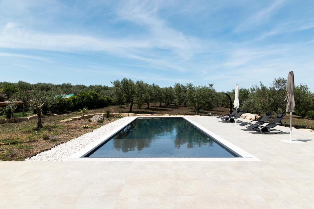 une piscine avec chaises et parasols sur un patio dans l'établissement Relais Donna Tana, à Buseto Palizzolo