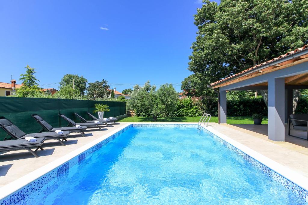 a swimming pool with lounge chairs next to a house at Wonderful villa wit pool surrounded by nature, high level of privacy a few minutes by the beach and town center by car in Valtura