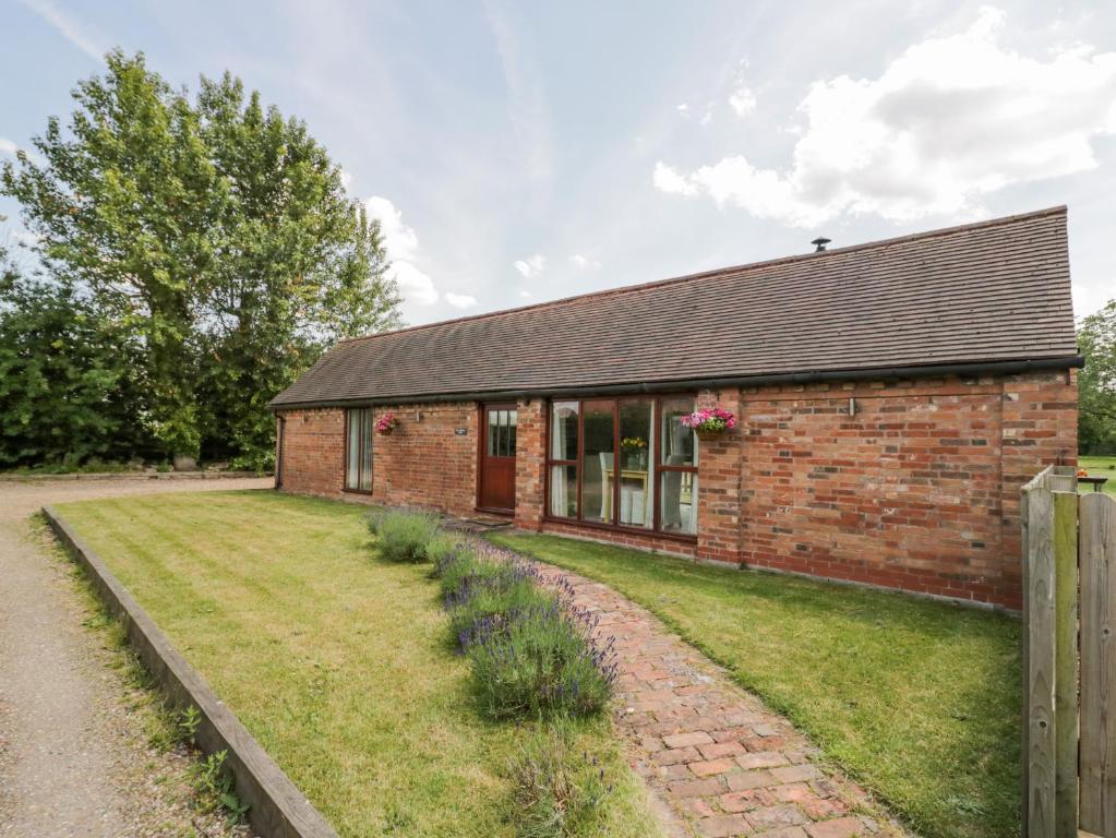 an old brick house with a grass yard in front of it at The Chicken Shed in Warwick