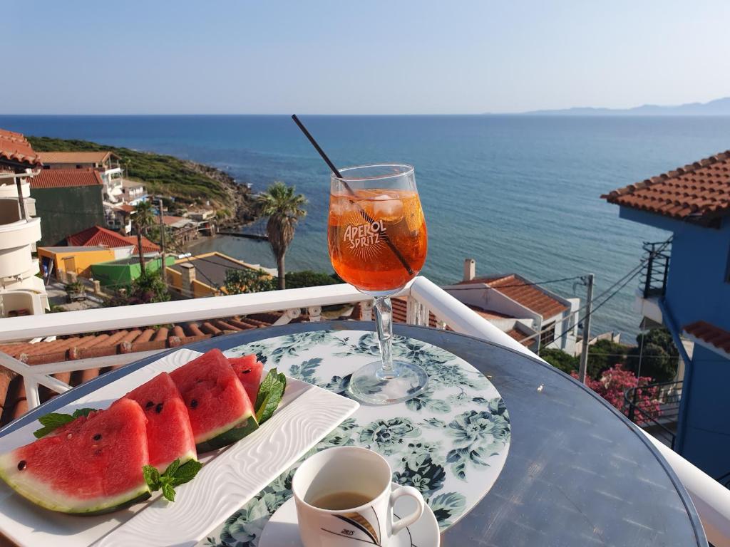 a table with a plate of watermelon and a drink at Brati II Beach Hotel in Arkoudi