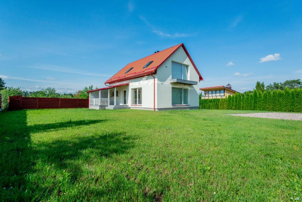 una casa con techo rojo en un campo de césped en Jaukus svečių namelis, en Druskininkai