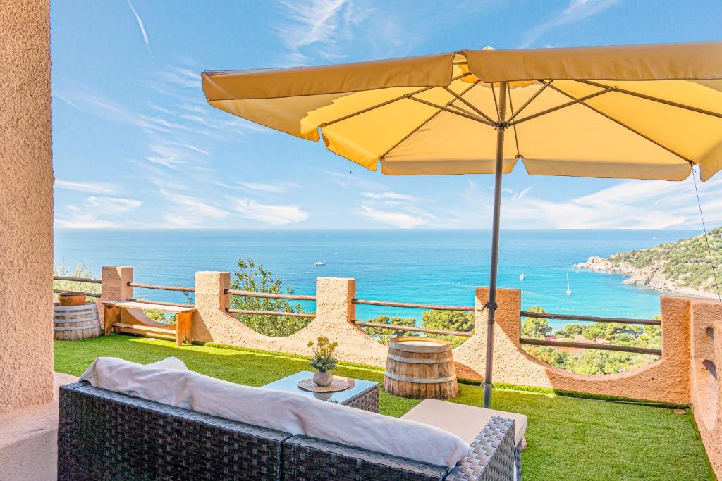 a patio with an umbrella and the ocean at Sardinia Villa Torre delle Stelle in Torre delle Stelle