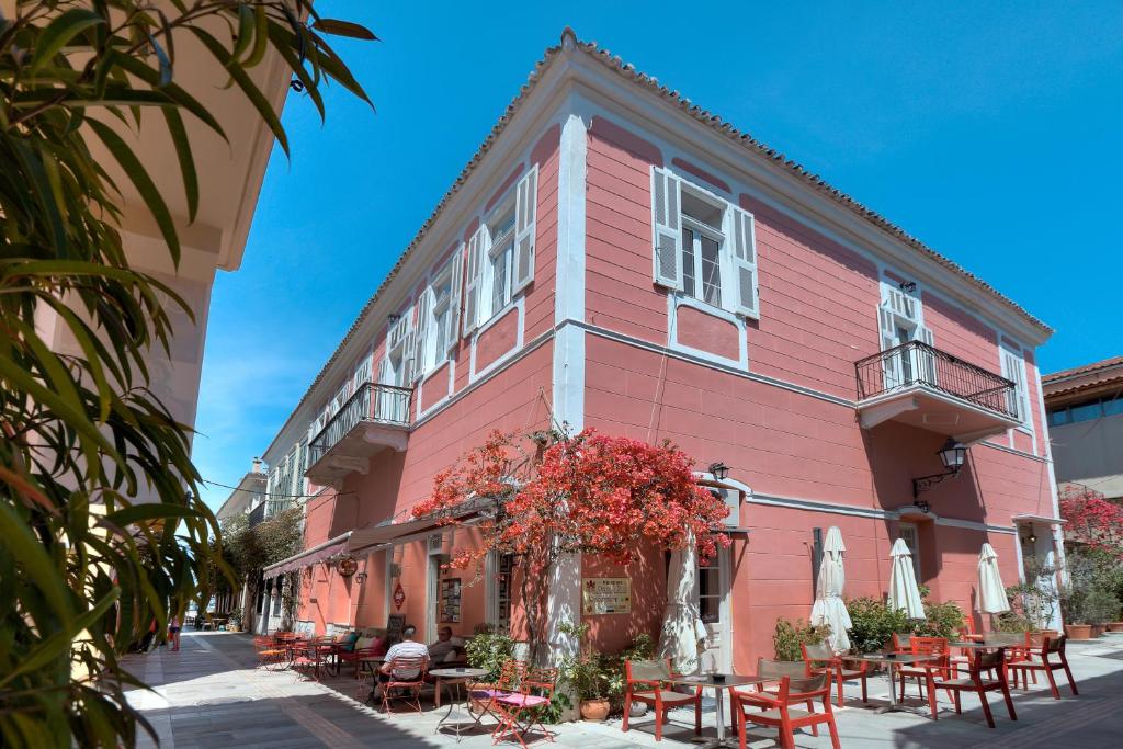a pink building with tables and chairs in front of it at Omorfi Poli in Nafplio