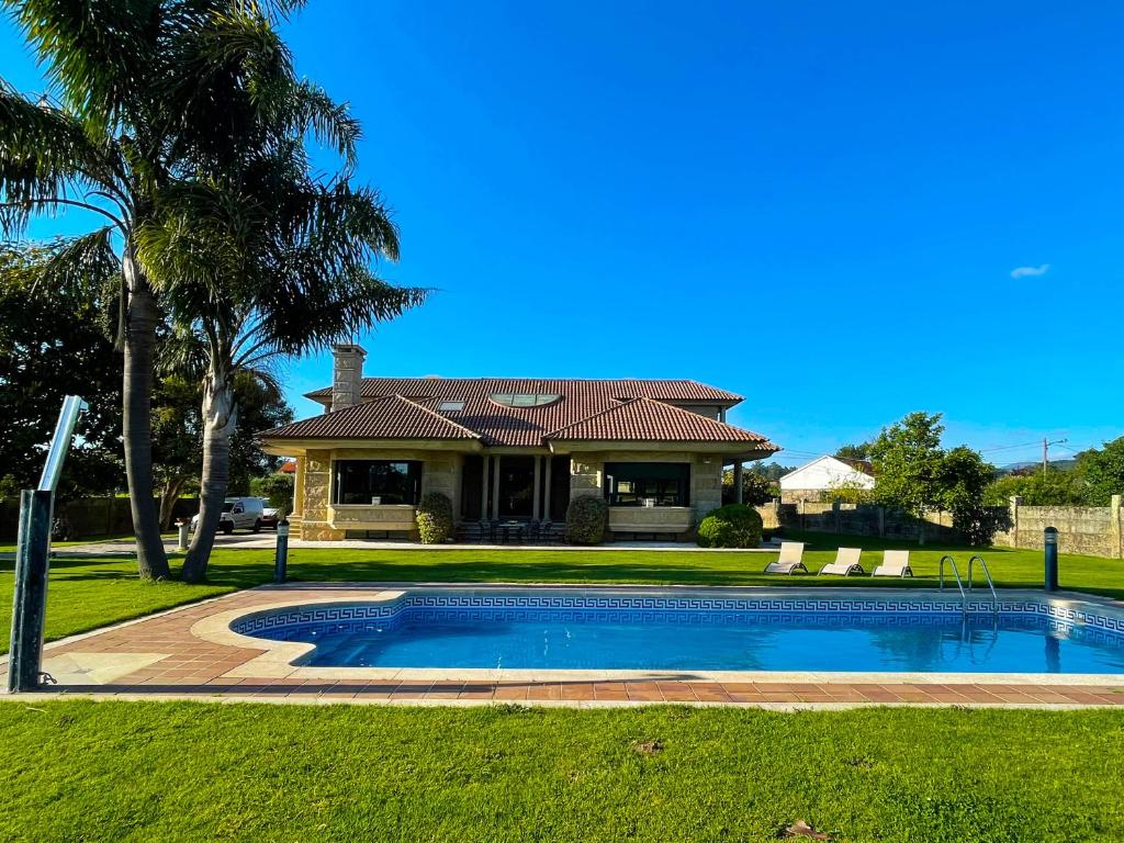 a house with a swimming pool in front of a house at Villa Remoan in Vilagarcia de Arousa