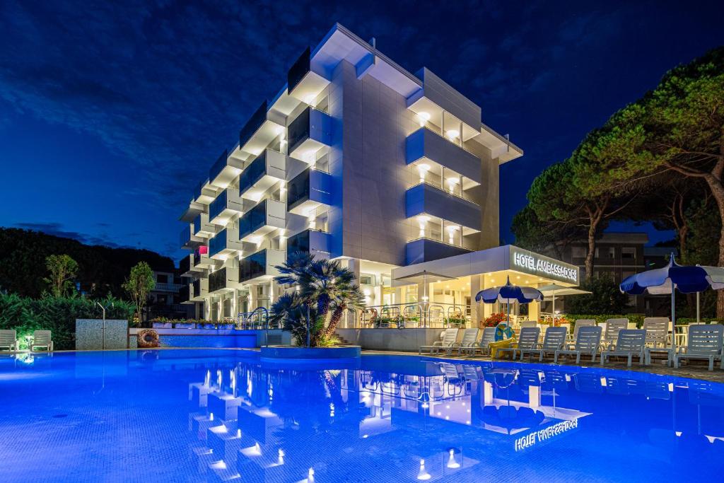un hotel con piscina di notte di Hotel Ambassador Meuble a Lignano Sabbiadoro