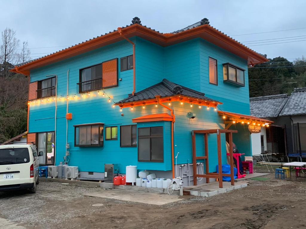 ein blaues Haus mit Lichtern an der Vorderseite in der Unterkunft Finecamp Guesthouse Share Room 相部屋 in Miyazaki