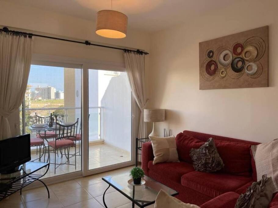 a living room with a red couch and a balcony at Caesar resort & SPA, Claudius 2 bedroom apartment, Iskele, Long beach in Saint Yeorgios