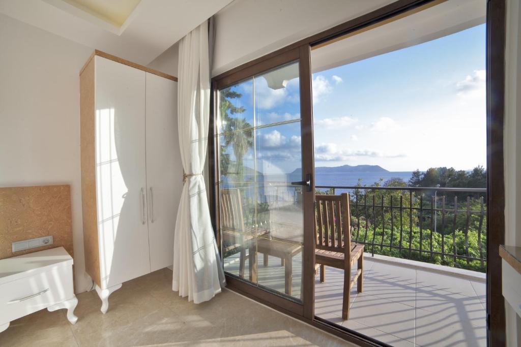 a room with a balcony with a chair and a window at Hotel Ferah in Kas