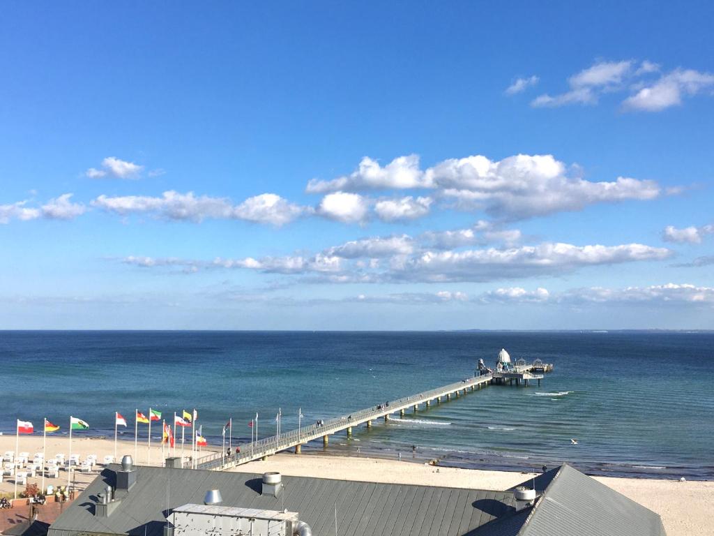 een pier op het strand met de oceaan en vlaggen bij Grömitz Center 8. Stock Meerblick in Grömitz