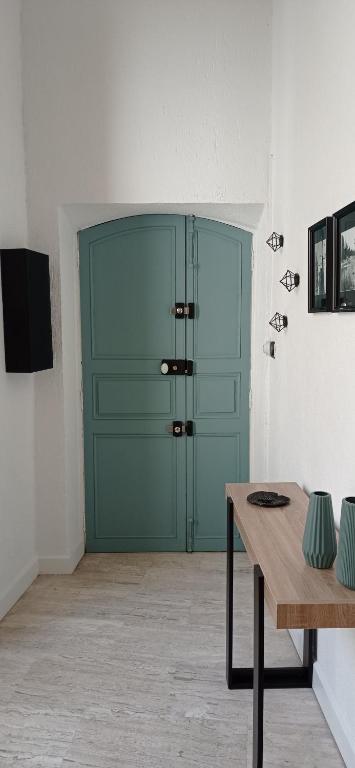 - une porte verte dans une chambre avec une table en bois dans l'établissement Chez Julie, triplex centre historique, à Béziers