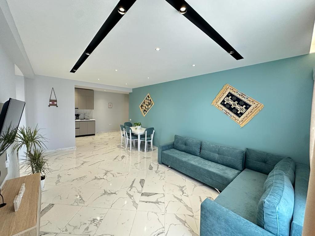 ein Wohnzimmer mit einem blauen Sofa und einem Tisch in der Unterkunft TreA Accomodations - Despacito Deluxe Sea View in Vlorë