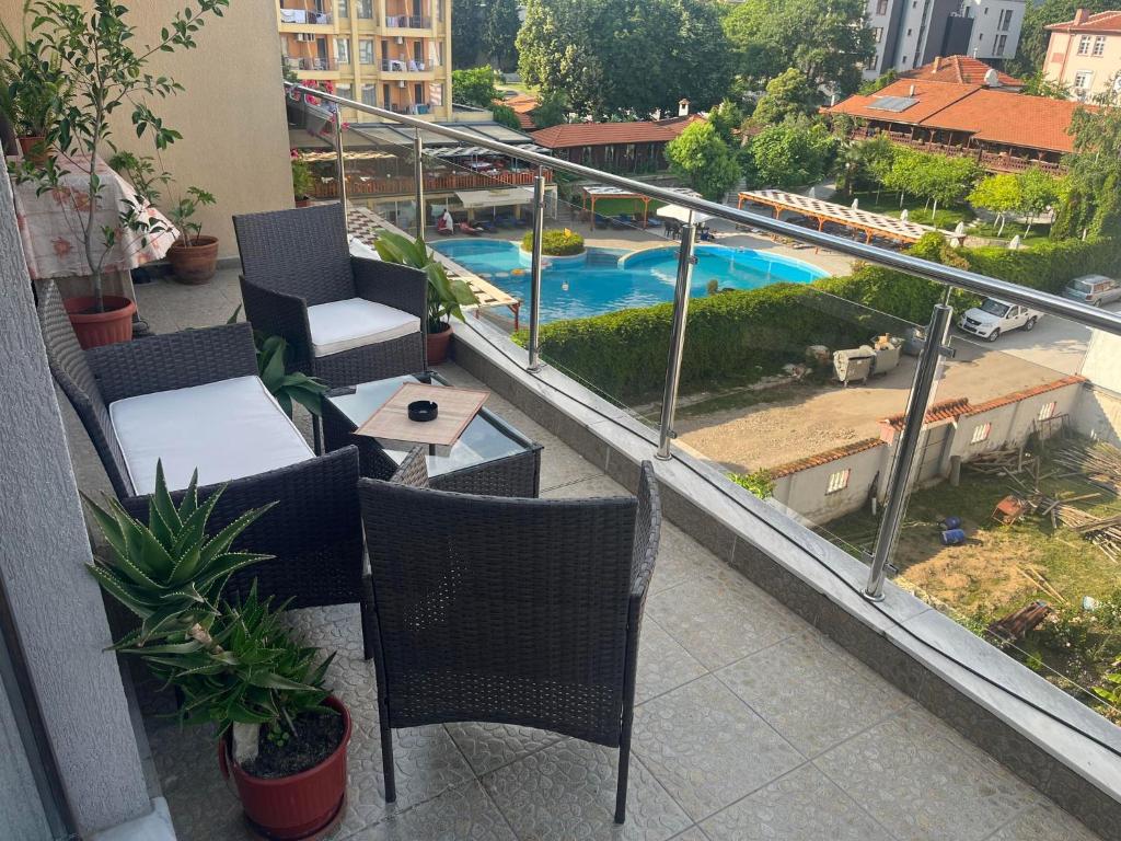 a balcony with chairs and a table and a swimming pool at Апартамент Панорама in Hisarya